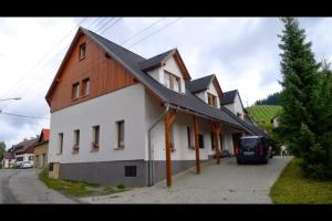 a large white house with a wooden roof at Aberto Jizerky in Albrechtice v Jizerských horách