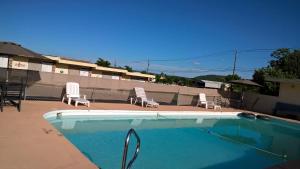 a swimming pool with two chairs and a table and chairs at Dogwood Motel in Mountain View