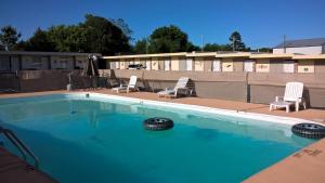 a large swimming pool with two lawn chairs and two chairs at Dogwood Motel in Mountain View