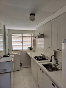 a kitchen with white cabinets and a sink and a window at Apartamento completo no coração de Goiânia in Goiânia