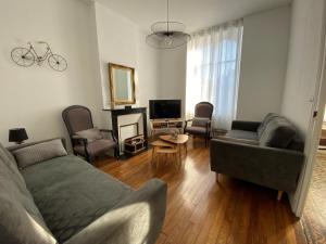 a living room with a couch and chairs and a tv at Maison années 30 avec jardin, piscine, proximité Loire, 4 chambres, vélos, idéale familles/amis - FR-1-590-261 in Bonny-sur-Loire