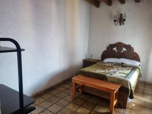 ein Schlafzimmer mit einem Bett und einer Bank daneben in der Unterkunft Casa Marte rústica in Oaxaca de Juárez