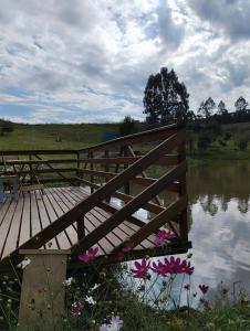 a wooden bridge over a body of water with flowers at Rancho dos lagos in Campo Alegre