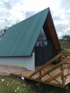 a house with a green roof and a wooden deck at Rancho dos lagos in Campo Alegre