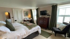 a bedroom with a bed and a chair and a television at Treveighan Farmhouse in Saint Teath