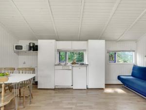 a kitchen with white appliances and a table and a blue couch at 4 person holiday home in Hampen in Hampen