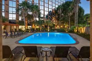 une piscine avec des chaises et un bâtiment dans l'établissement Sheraton Houston Brookhollow Hotel, à Houston