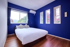 ein Schlafzimmer mit blauen Wänden und einem Bett mit Kissen in der Unterkunft ブルースカイ富士 in Fujikawaguchiko