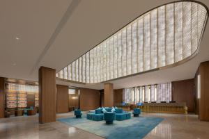 a large lobby with blue chairs and a large window at 西安明城墙永兴坊桔子水晶酒店 in Xi'an