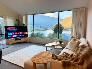 a living room with a couch and a large window at 3BR Lakeview Home with Balcony, Parking, Near Marina in Queenstown