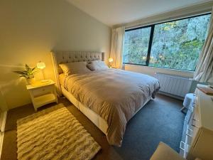 a bedroom with a bed and a large window at 3BR Lakeview Home with Balcony, Parking, Near Marina in Queenstown