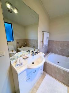 a bathroom with a sink and a tub and a mirror at 3BR Lakeview Home with Balcony, Parking, Near Marina in Queenstown +34 photos