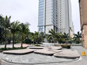 a large building with palm trees in a courtyard at Dcapitale - Feria Homes in Hanoi