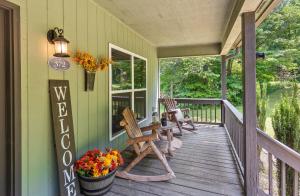 a porch with two chairs and a table and flowers at Updated Cabin - Hiwassee Highlife in Decatur