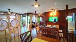 a living room with chairs and a tv on a wall at The Bukit Resort Langkawi in Kampung Padang Masirat