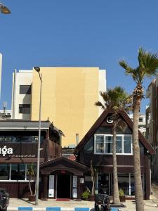 Bel appartement face là mer في القنيطرة: مبنى أمامه أشجار نخيل