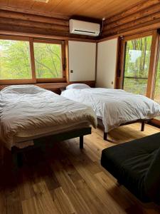 two beds in a room with two windows at スターダスト高山 in Nakayama