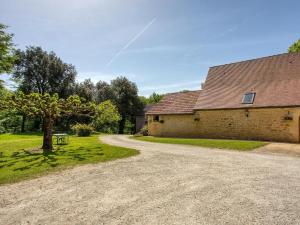 a dirt road next to a building with a tree at Charmant gîte avec jardin, clim, wifi, proche Sarlat et rivière Dordogne, animaux bienvenus - FR-1-616-310 in Carlux
