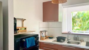 a kitchen with a sink and a window at Des Racines & Des Ailes in Petit-Bourg