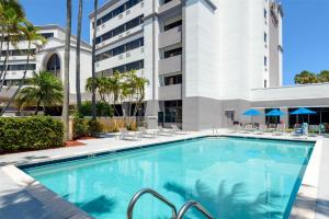 a swimming pool with chairs and a building at DoubleTree by Hilton Hotel West Palm Beach Airport in West Palm Beach