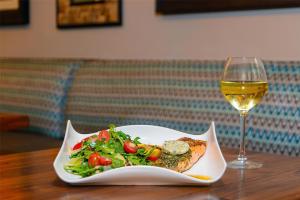 a plate of food and a glass of wine on a table at DoubleTree by Hilton Hotel West Palm Beach Airport in West Palm Beach