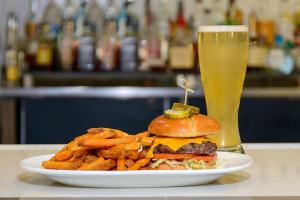 a plate with a hamburger and french fries and a glass of beer at DoubleTree by Hilton Hotel West Palm Beach Airport in West Palm Beach