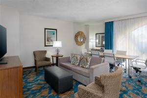 a living room with a couch and a table and chairs at DoubleTree by Hilton Hotel West Palm Beach Airport in West Palm Beach