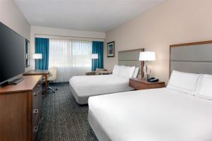 a hotel room with two beds and a flat screen tv at DoubleTree by Hilton Hotel West Palm Beach Airport in West Palm Beach