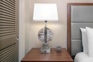 a lamp on a table next to a bed at DoubleTree by Hilton Hotel West Palm Beach Airport in West Palm Beach