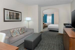 a hotel room with a couch and a bed at DoubleTree by Hilton Hotel West Palm Beach Airport in West Palm Beach