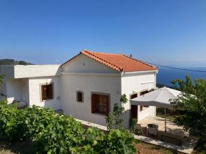 a white house with a table and an umbrella at Manolates 360 in Manolátes +19 photos