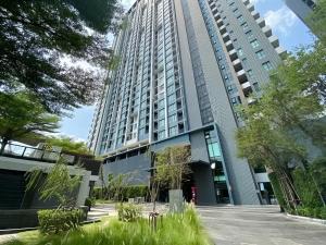 a tall building with a lot of grass in front of it at The Base - Rama 9 by Sumaq Property in Bangkok