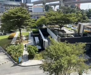 a building with trees in the middle of a city at The Base - Rama 9 by Sumaq Property in Bangkok