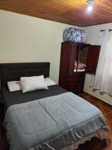 a bedroom with a bed and a dresser at Casa Aconchego Serrano in Campos do Jordão