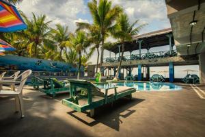a resort with a pool with green benches and palm trees at Hotel Playa Paraíso in Monterrico +18 photos