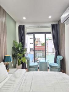 a bedroom with a bed and chairs and a window at APEC Hotel in Ho Chi Minh City