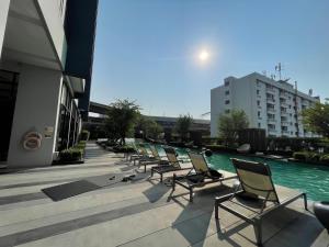 a row of chairs sitting next to a swimming pool at The Base - Rama 9 by Sumaq Property in Bangkok