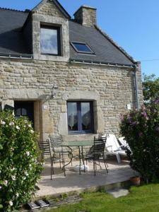 a patio with a table and chairs in front of a building at Ty breizh in Plumelec