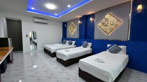 a hotel room with two beds and a blue wall at Art Nara Hotel อาร์ตนรารีสอร์ท in Narathiwat