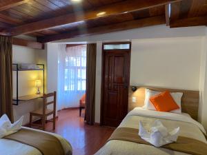 ein Schlafzimmer mit zwei Betten und einer Holzdecke in der Unterkunft Juliet's House in Ollantaytambo