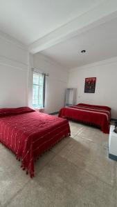 two beds in a white room with red sheets at Casa Porfirio in Oaxaca City