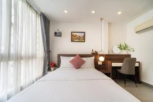 a bedroom with a large white bed and a desk at Galaxy Boutique Sai Gon Central Hotel in Ho Chi Minh City