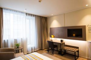 a hotel room with a desk and a room at Home Inn Plus Shanghai Xintiandi Lujianbang Road Subway Station in Shanghai
