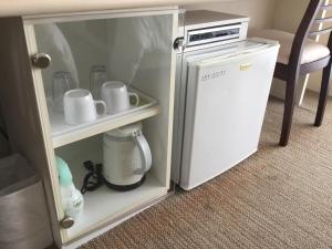a small white refrigerator in a room with a chair at Hotel Gran View Garden Okinawa in Tomigusuku