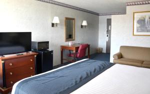 a hotel room with a bed and a tv and a desk at Travelodge by Wyndham Milwaukee in Milwaukee
