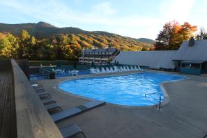 a large swimming pool with chairs and mountains in the background at Village of Loon Mountain - VI in Lincoln