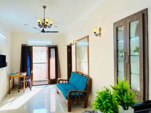 a living room with a blue chair and windows at Good stay TNagar in Chennai