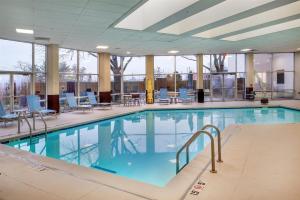 a large swimming pool with blue chairs and tables at Embassy Suites by Hilton St Louis Airport in Bridgeton
