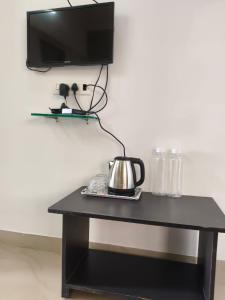 a black table with a tea kettle and a tv on a wall at Panchgani Palace in Panchgani
