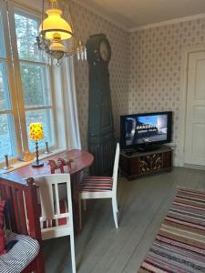 a living room with a clock and a table and a television at SwedishCountryLiving / Skippers cottage in Köpmannebro
